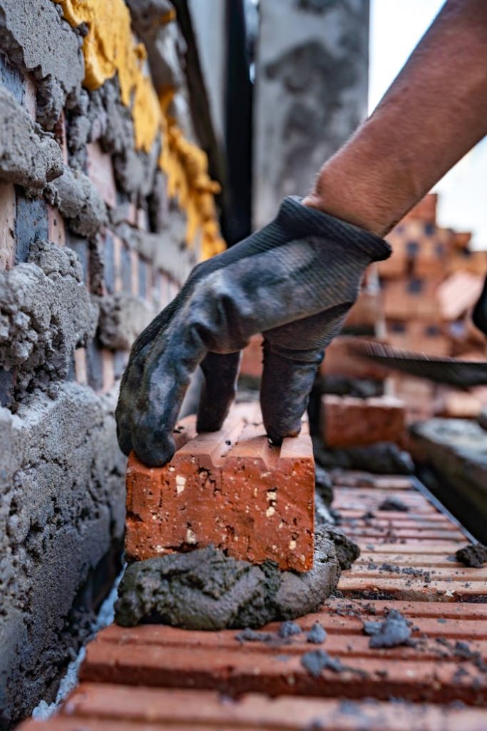 A bricklayers gloved hand places a brick on a construction site in Vietnam.